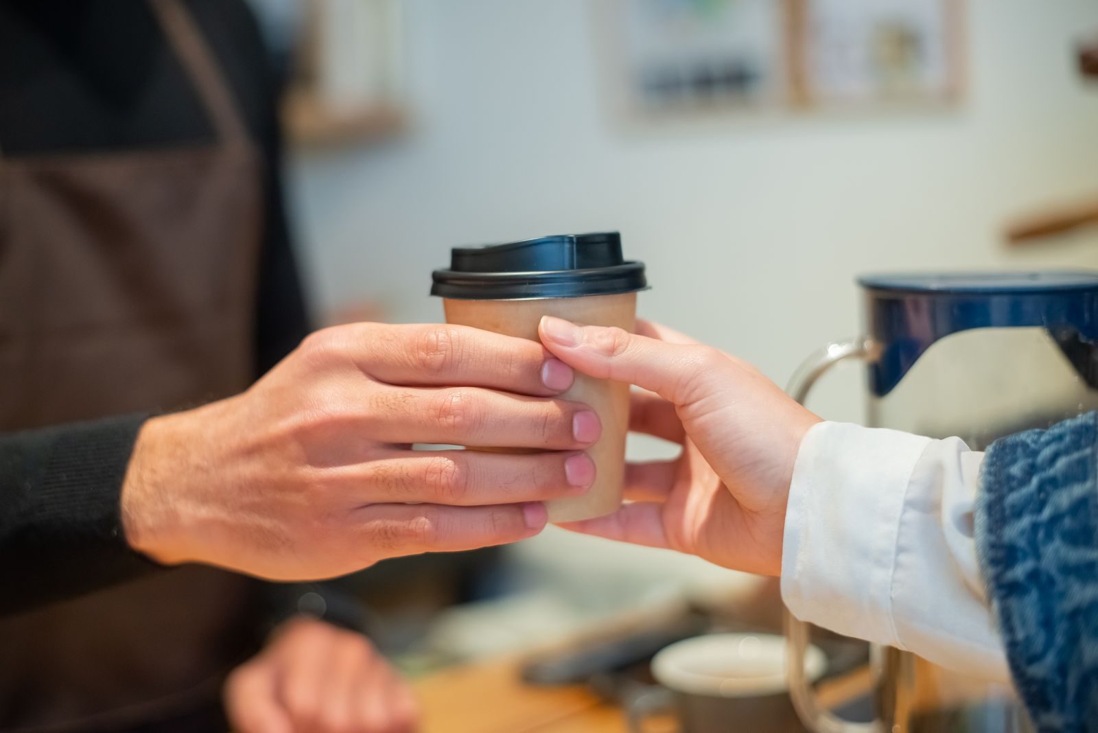 A barista handing a coffee to a happy customer at a cafe counter