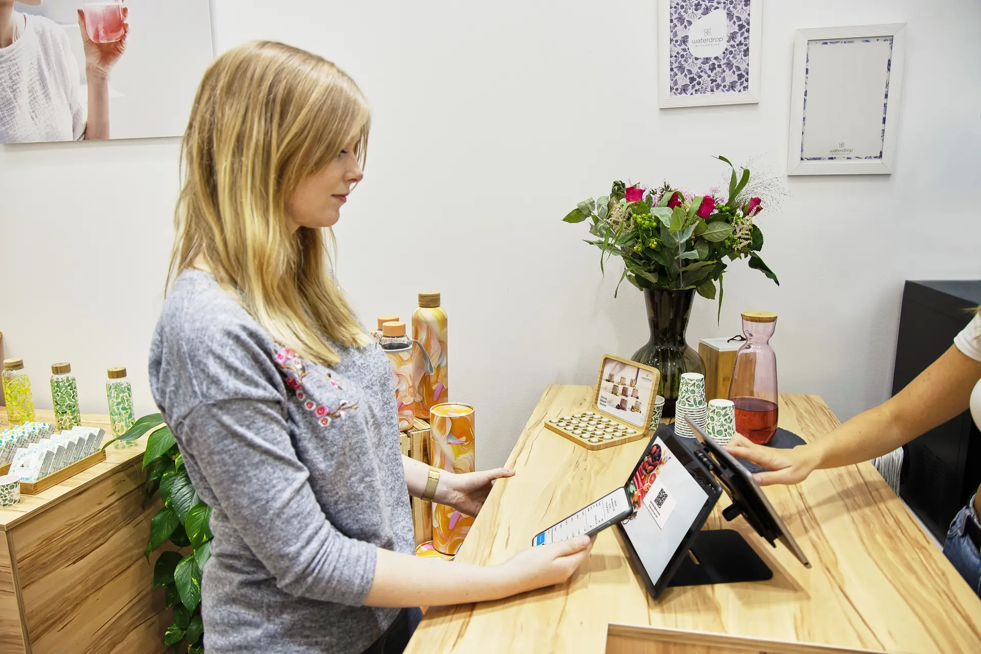 A customer checking her phone at a shop counter