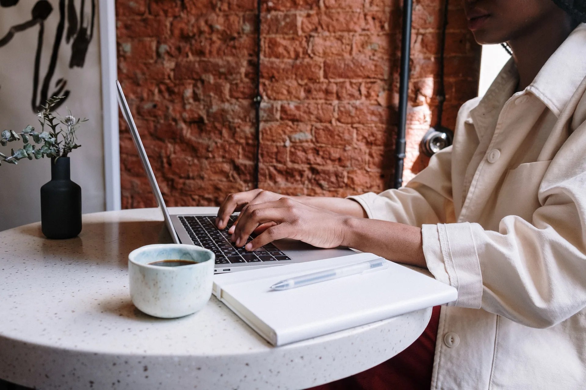 A small business owner writing in a notebook beside a laptop