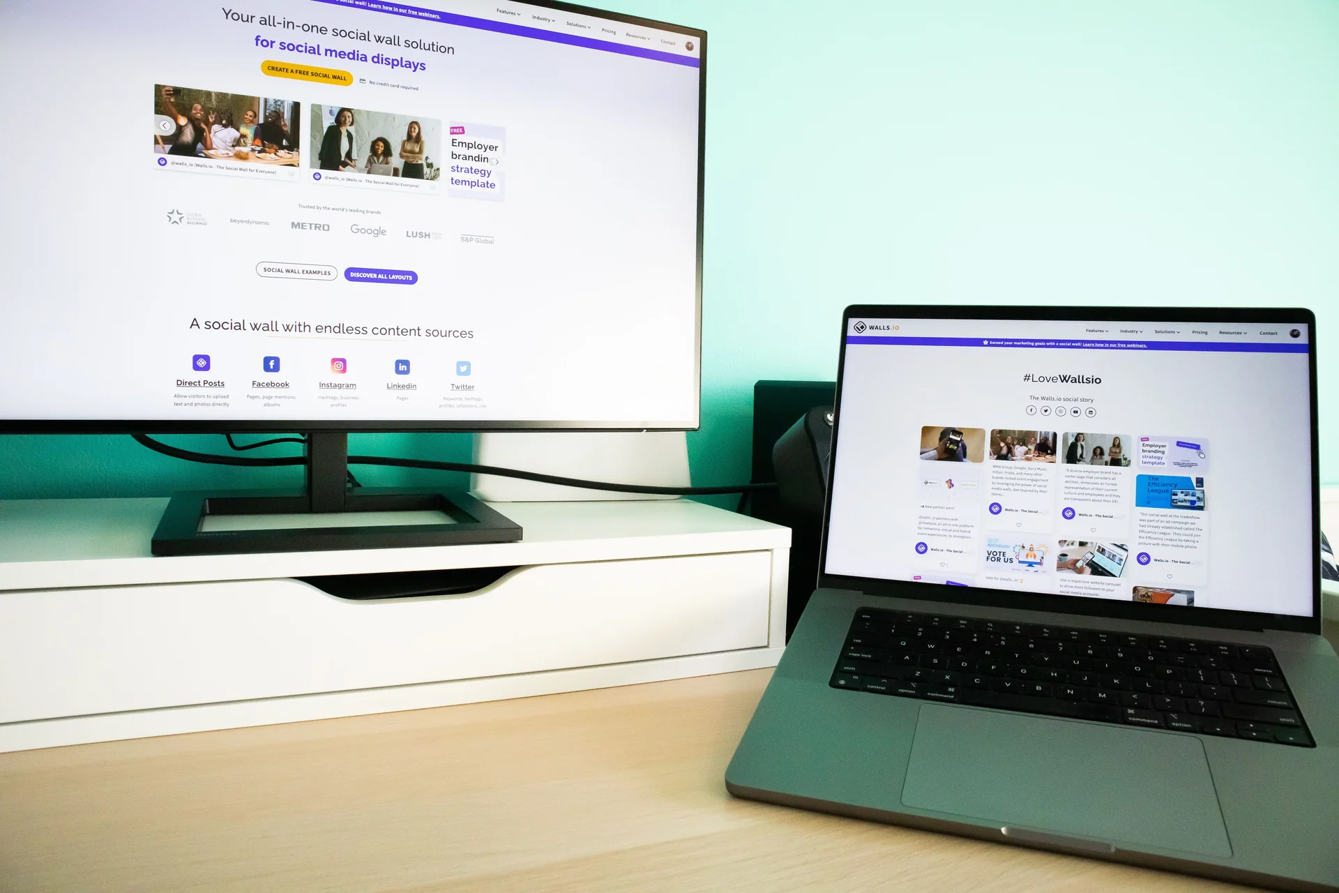 A desk with a laptop and a monitor showing website pages