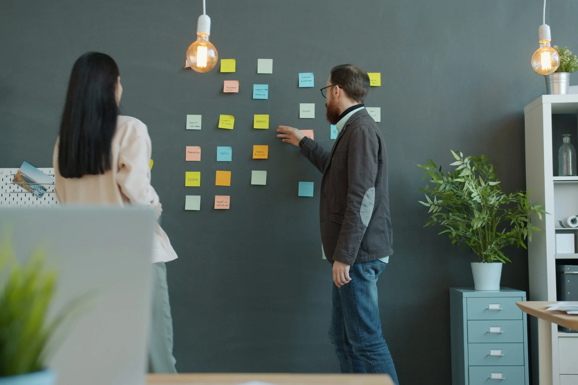 Two people planning with sticky notes on a wall